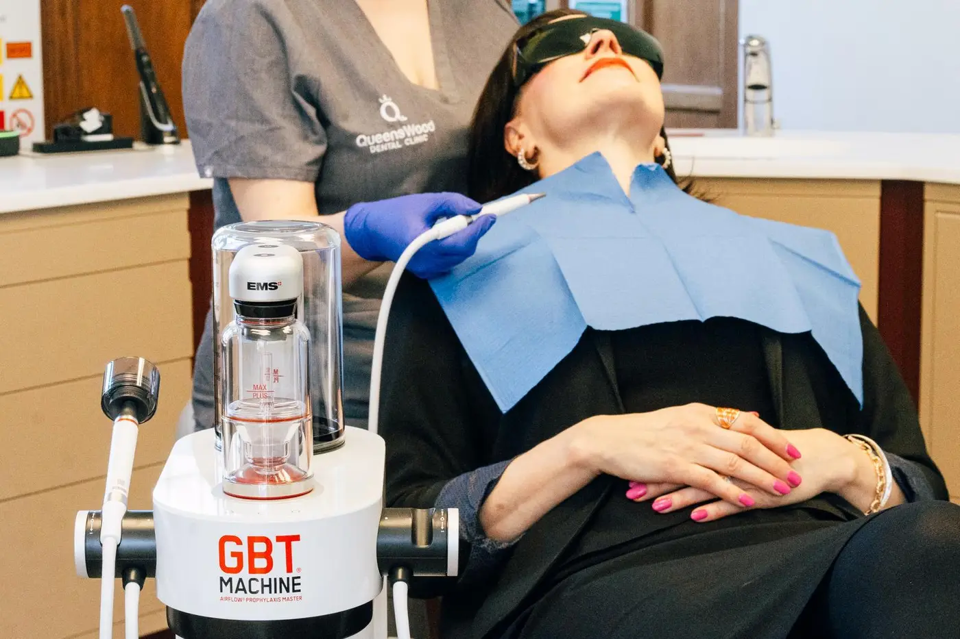 A QueensWood hygienist using the EMS AirFlow handpiece during a Guided Biofilm Therapy appointment